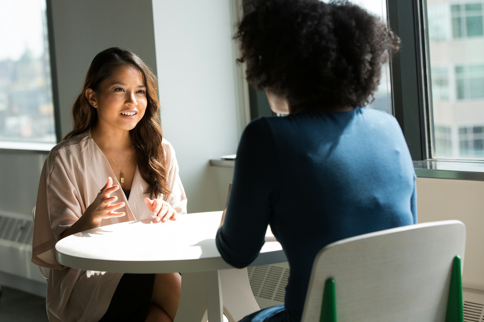 Two people in conversation across a table, as in a mediation session